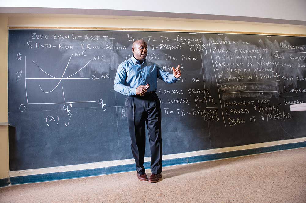 Applied Economics professor teaches in front of a chalkboard.