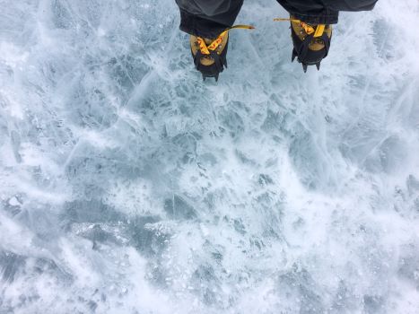 Feet in yellow boots walking on ice in Antarctica.