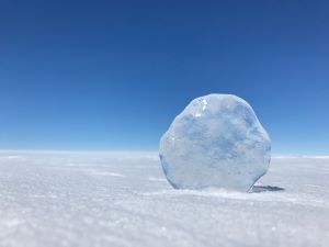 Chunk of ice on snow against blue sky in Antarctica.