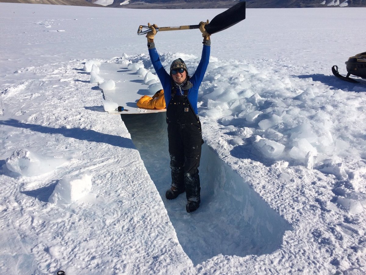 Heidi Roop working in Antarctica on the ice with a shovel.