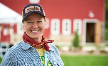 Woman wearing a trucker hat and bandana around her neck.