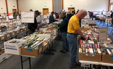 People search through books at a sale.
