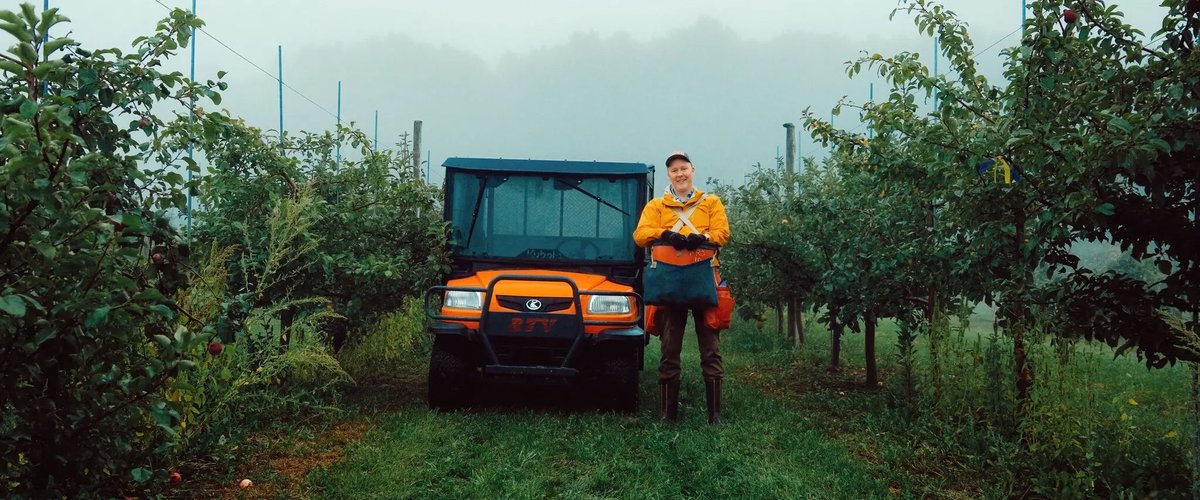 Sean Myles, founder of the Apple Biodiversity Collection in Novia Scotia, stands in an apple orchard next to an orange four wheeler.