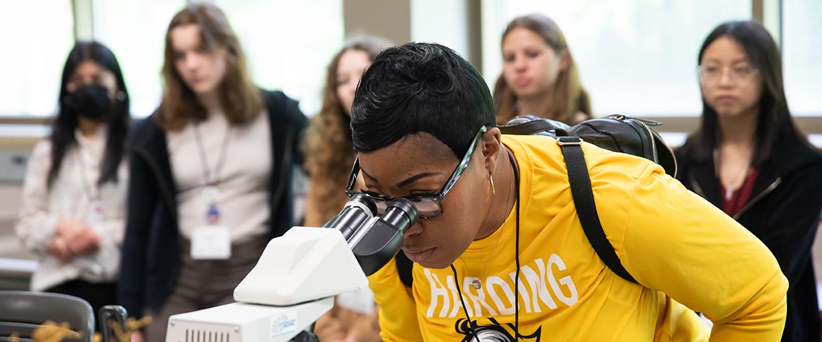 A high school student looking in a microscope at MNYI event.