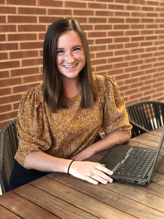 Applied economics alumna Tory Bradley sits at a table near her lap top.
