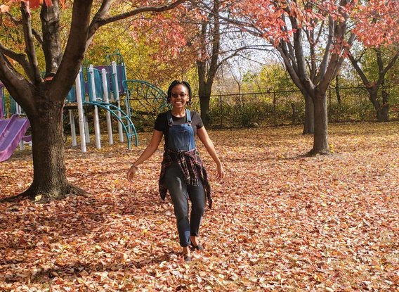 Dorah Mwangola at a park with fallen leaves.