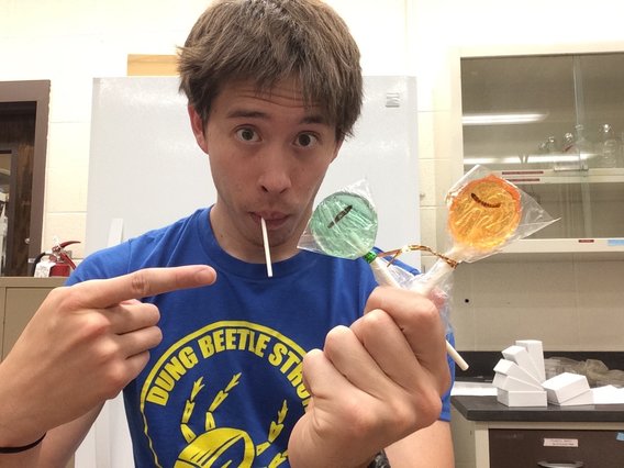 Graduate student eating a lollipop that contains a bug.