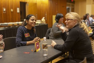 Two people sit at a table during an alumni connectors gathering.