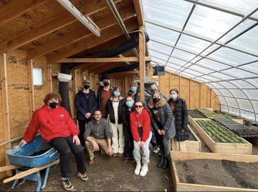 Students gather in a greenhouse.