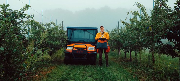 Sean Myles, founder of the Apple Biodiversity Collection in Novia Scotia, stands in an apple orchard next to an orange four wheeler.