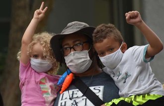 Plant science student Bryant Jones with two kids, one holding up a fist and the other, a peace sign.
