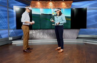 Professor Heidi Roop talks on air with TV journalist while wearing VR goggles.