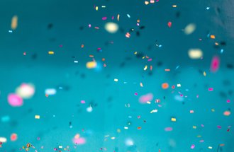 Multi-colored confetti against a turquoise background.