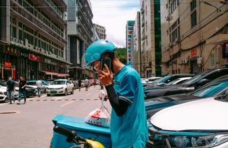 Food delivery person talking on phone by his bicycle.