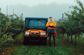  Sean Myles, founder of the Apple Biodiversity Collection in Novia Scotia, stands in an apple orchard next to an orange four wheeler.