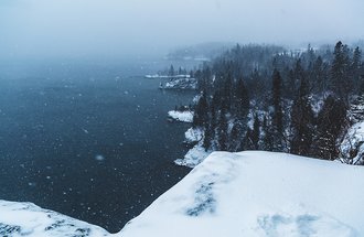 A wintery, snowy view of Lake Superior from atop a cliff in Tettegouche State Park.