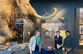 A photo of people standing in front of a wooly mammoth at the Bell Museum